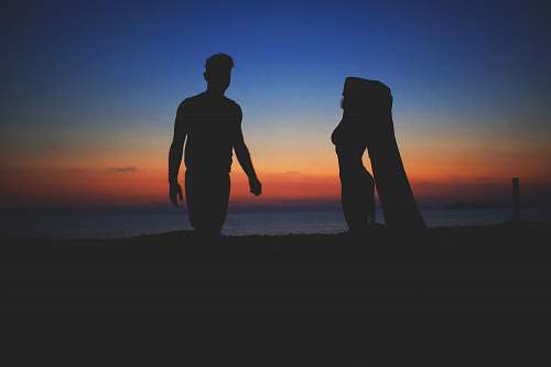 human silhouette photo of man and woman near beach people