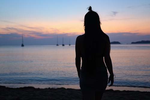 human silhouette photography of woman standing on seashore standing