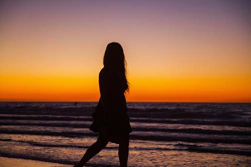 human silhouette photography of woman walking on seashore standing