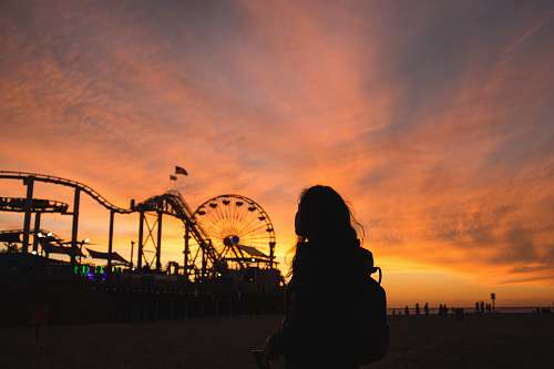 human silhouette photography of woman with view of amusement park ferris wheel