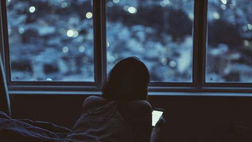 window woman holding phone near window during daytime back