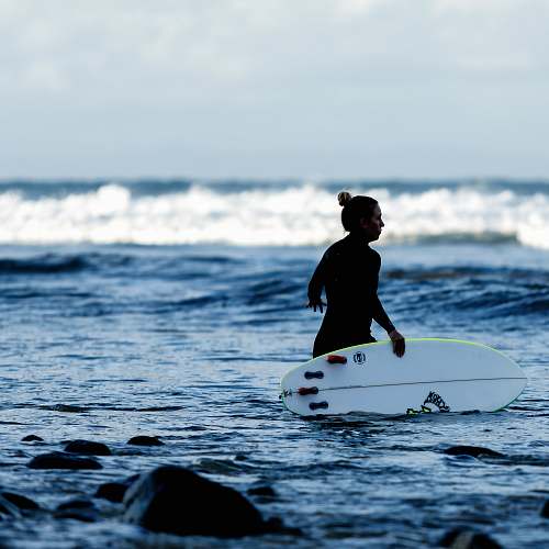 waves woman holding white surfboard on body of water sport