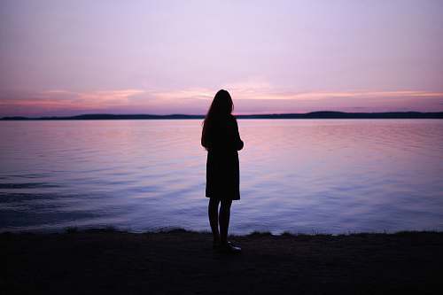 people woman standing near body of water during golden hour human