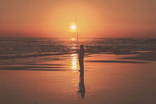 asilah silhouette photography of person holding fishing rod near body of water morocco