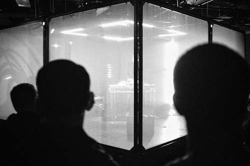 black-and-white backview of people looking to glass room grey