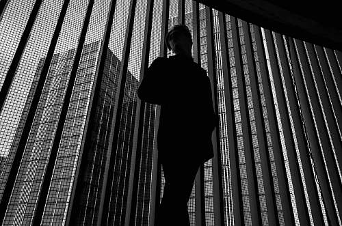 human grayscale photo of man near window black-and-white