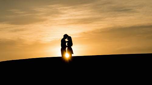 couple man and woman's silhouette on hill during golden hour man