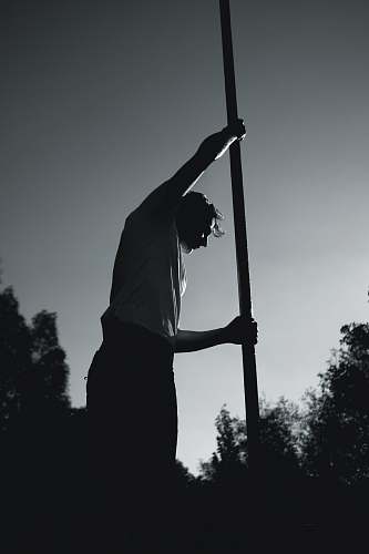 man man in white shirt holding pole grey