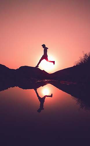 nature man jumping on rock beside lake outdoors