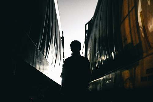 gap man standing between building silhouette between trains