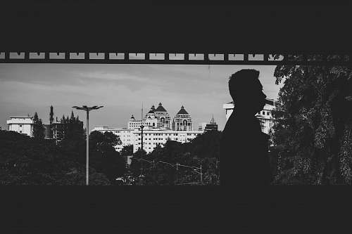 black-and-white man standing near building grey