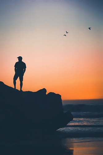 person man standing on rock near on seashore people