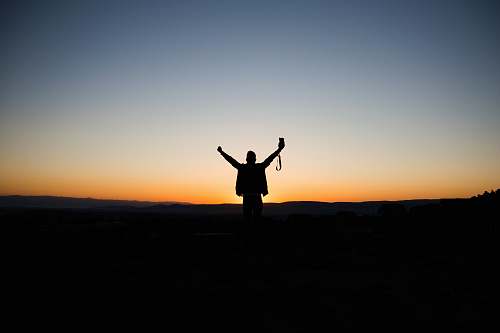 nature man stretching his arms silhouette at sunrise outdoors