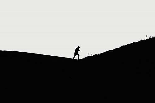 black-and-white man walking on hill standing