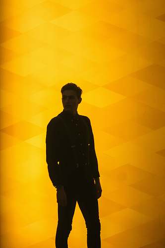 human man wearing black dress shirt standing near yellow background person