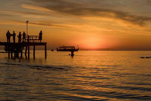 sunset photo of people on sea dock during sunset pier