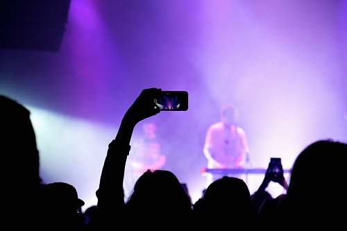 person photography of person holding smartphone capture video during concert human