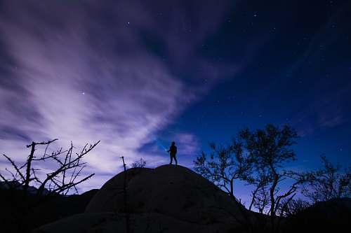 stars silhouette of a person on mountain hill trees