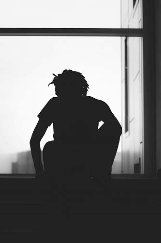 human silhouette of a person sitting near window black-and-white