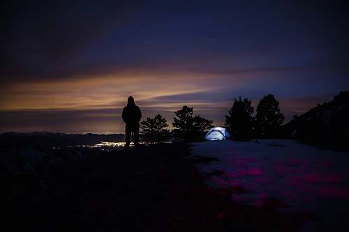person silhouette of hooded person with tent in background camping