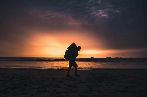nature silhouette of man carrying container standing on shoreline outdoors