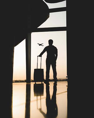 person silhouette of man holding luggage inside airport people