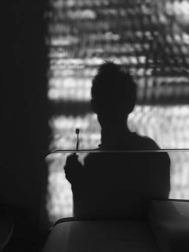 black-and-white silhouette of man holding toothbrush grey