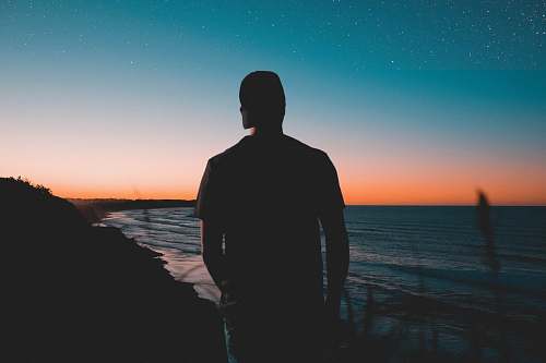 nature silhouette of man near body of water outdoors