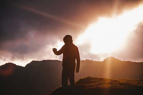 sunset silhouette of man on cliff man