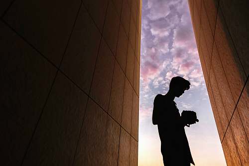 person silhouette of man standing between buildings human
