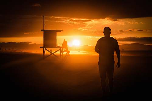 person silhouette of man standing near wooden shed during sunset newport beach