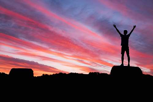 sky silhouette of man standing on high ground under red and blue skies sunset