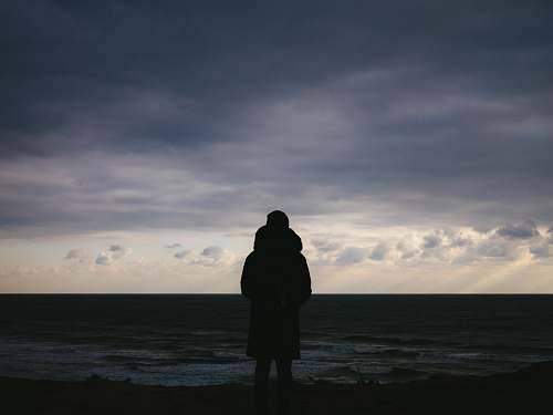 human silhouette of man standing on plains under cloudy sky during daytime person