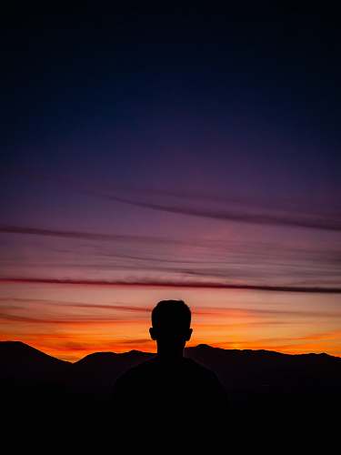 person silhouette of man standing with mountain on horizon human