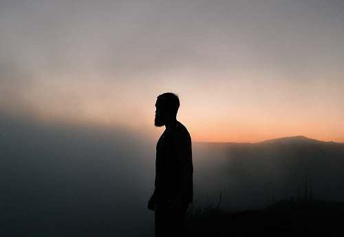 human silhouette of man surrounded with fog during golden hour person