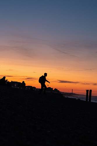 human silhouette of man walking on seashore person