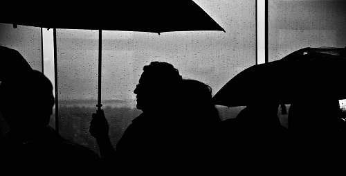 human silhouette of people holding umbrella black-and-white