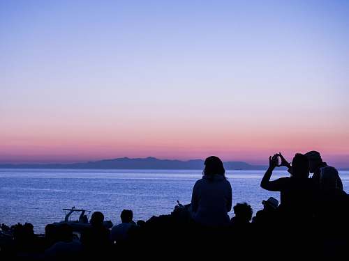 human silhouette of people on beach watching setting sun person