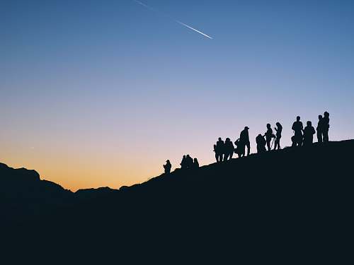 sunset silhouette of people on mountain under falling satr sky