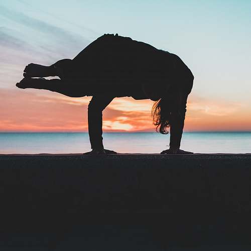 water silhouette of person doing hand stand shoreline