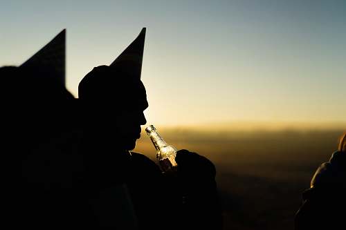 person silhouette of person holding bottle during orange sunset bottle