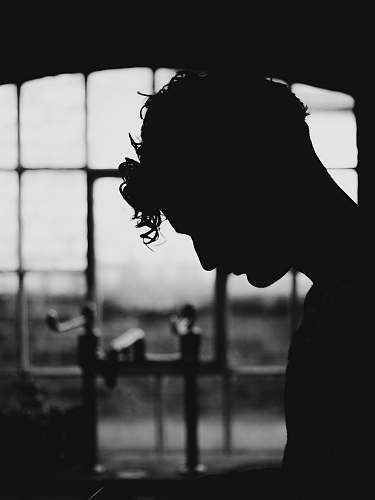 black-and-white silhouette of person near window grey