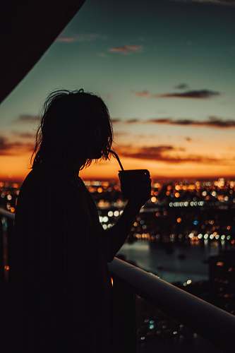 human silhouette of person sipping coffee on cup during golden hour person