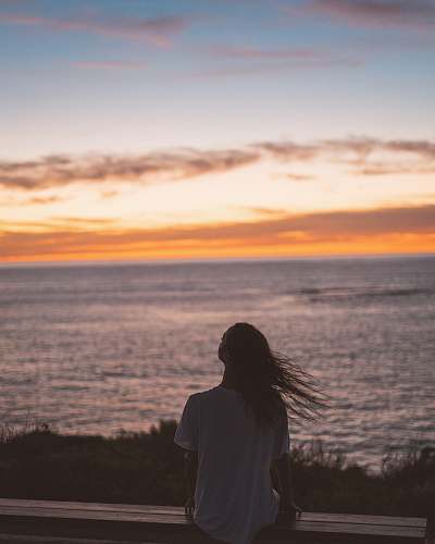 nature silhouette of person sitting near ocean during daytime outdoors