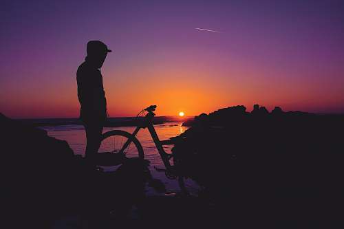 human silhouette of person standing near bicycle person