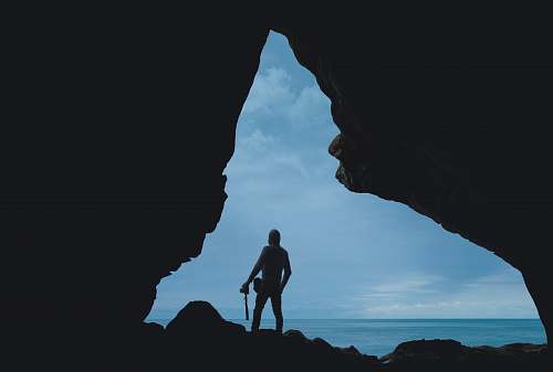 person silhouette of person standing on rock blue