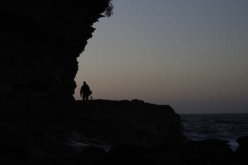 outdoors silhouette of person walking beside beach grey