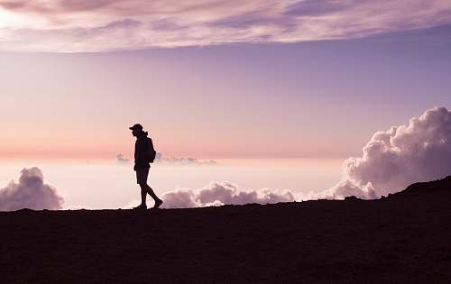 person silhouette of person walking under white clouds people