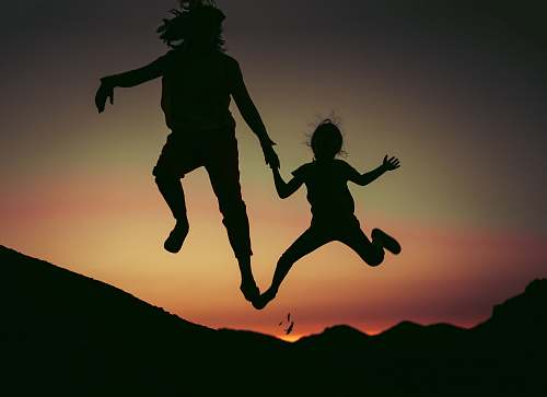 human silhouette of two children jumps person