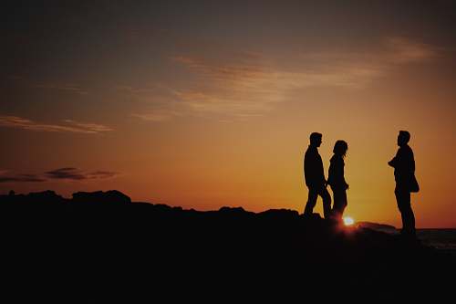 brown silhouette of two men and one woman on mountain laguna beach